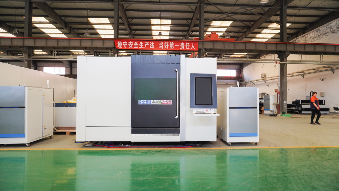 Enclosed fiber laser cutting machine in the workshop, showing the access doors, viewing windows and operator station.