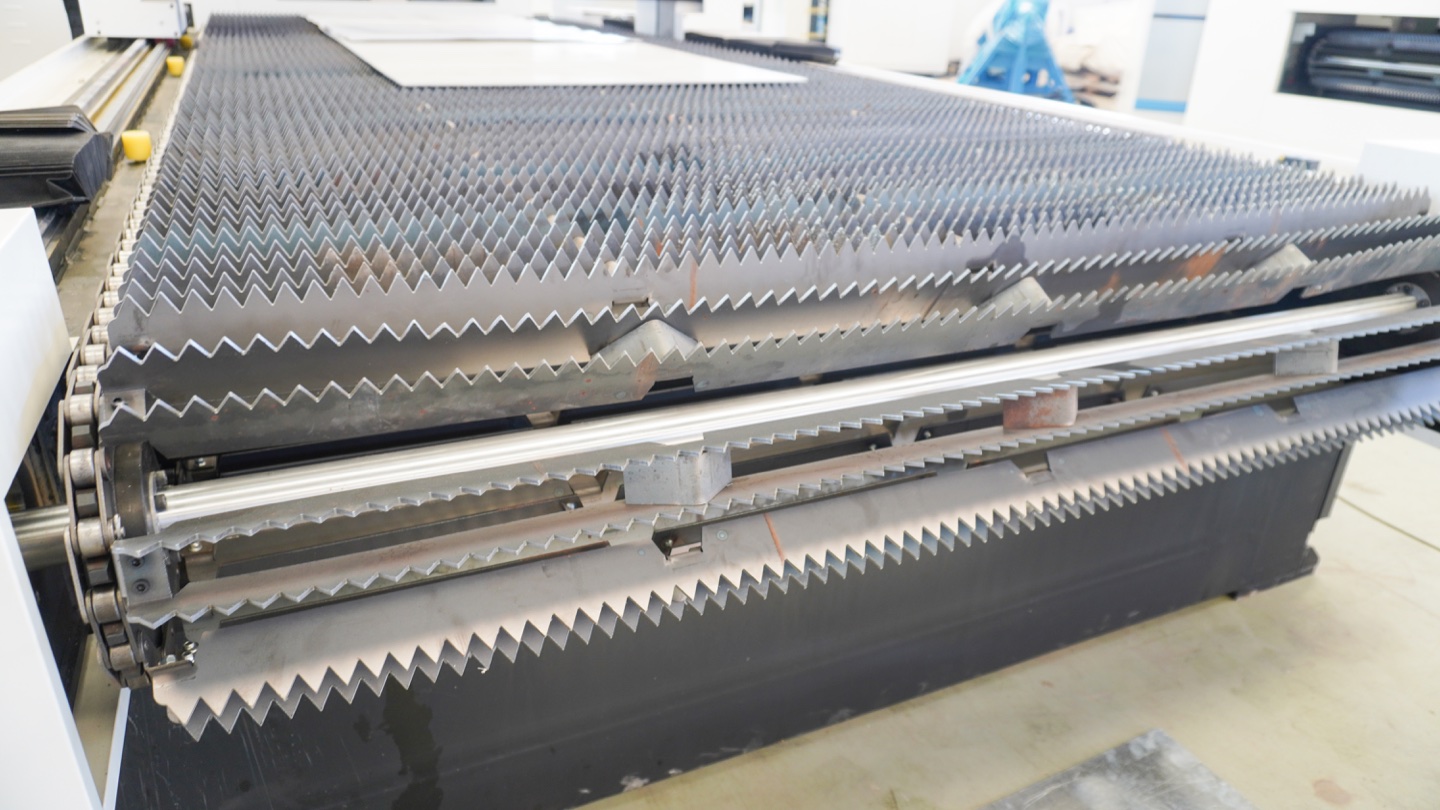 Sheet-feeding and support structure at a laser cutting machine; material handling contributes to production time and cost.