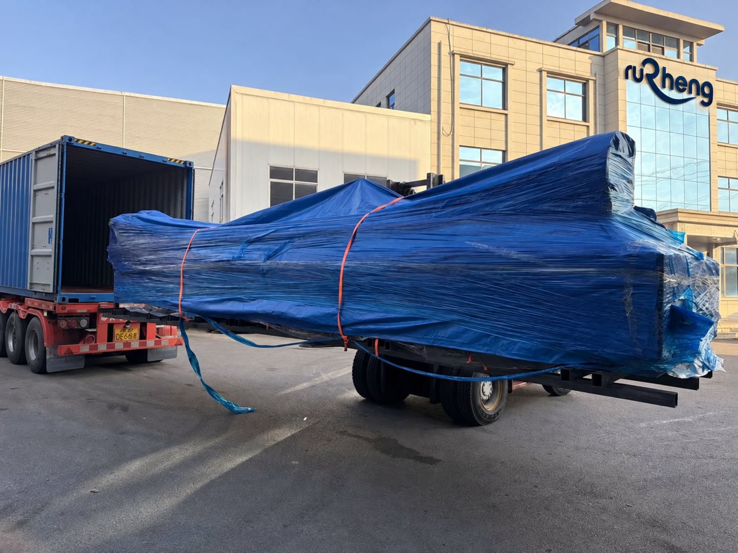 Wrapped laser cutting equipment during loading; building signage adapted to Rucheng.