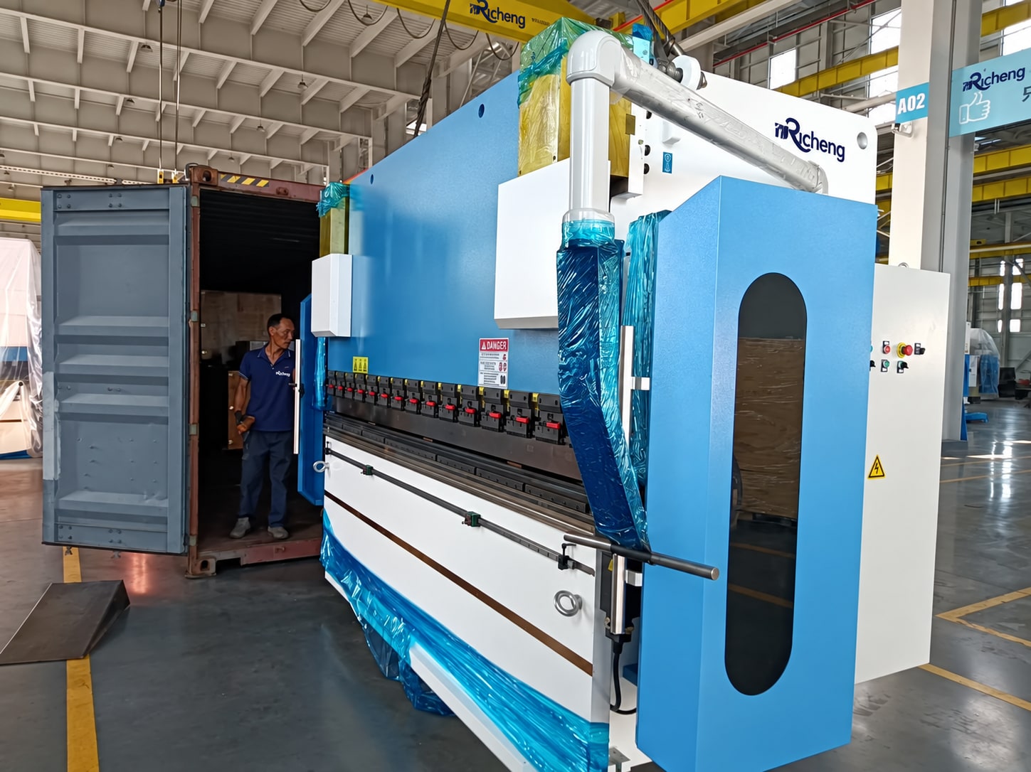 Press brake during container loading; visible workshop branding adapted to Rucheng.