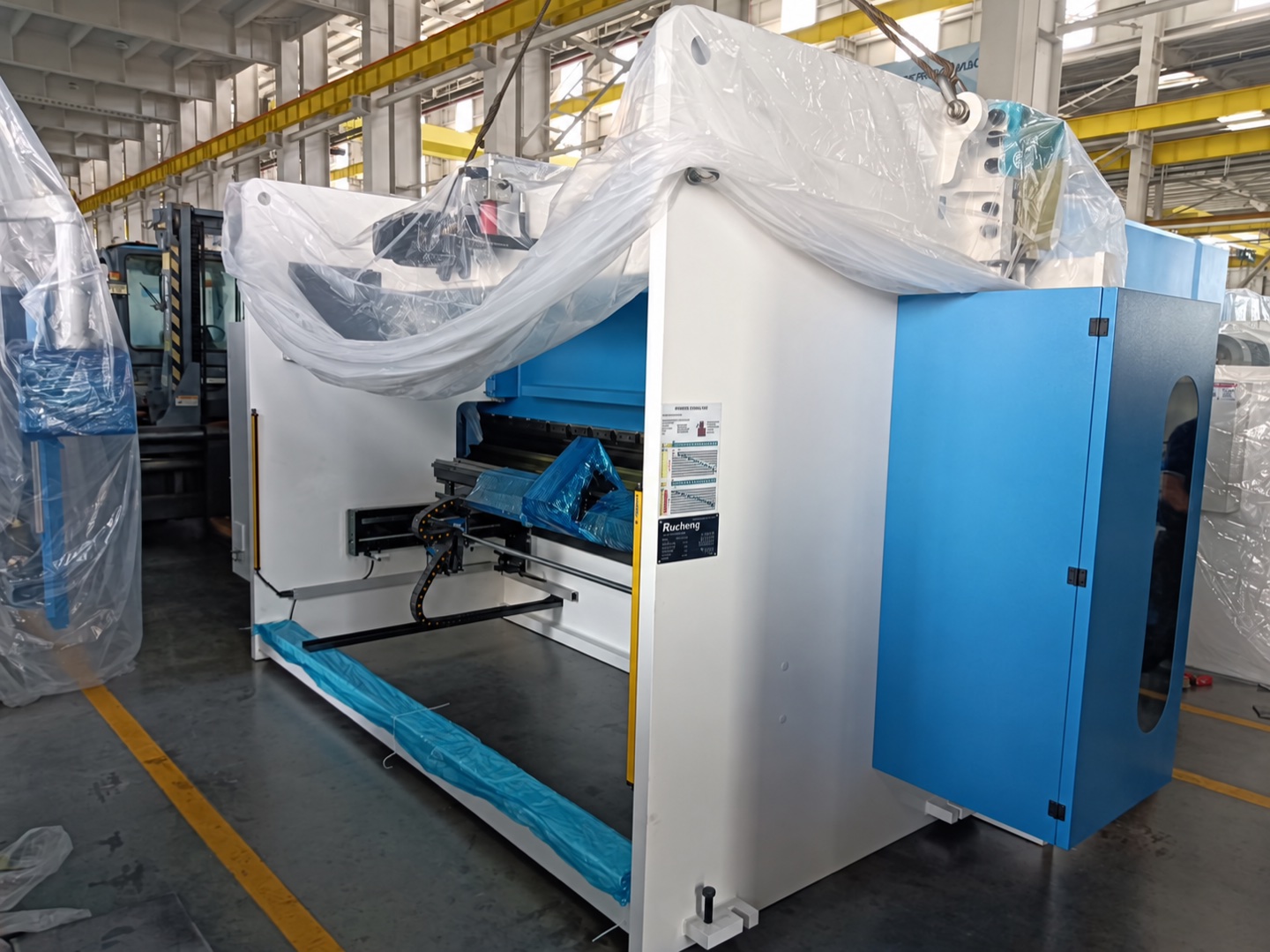 Machine surfaces covered before loading; manufacturer branding on the machine plate adapted to Rucheng.